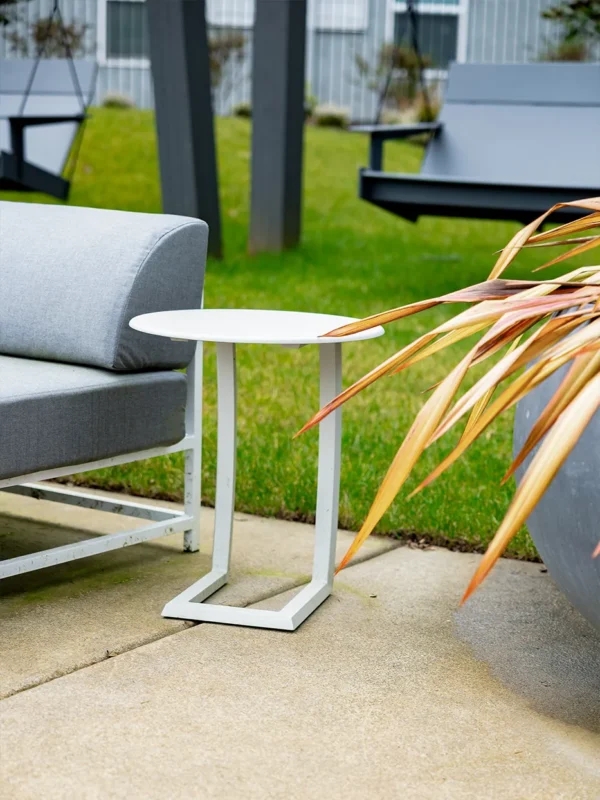 Modern outdoor sofa and side table in a serene green setting for relaxation.