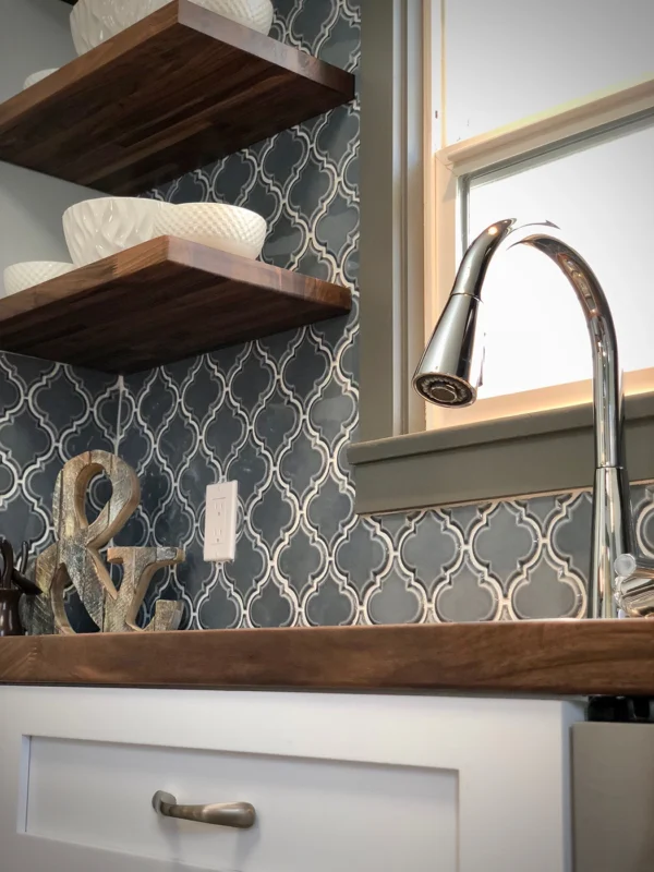 Stylish modern-rustic kitchen corner with elegant sink, wooden shelves, and decorative accents.