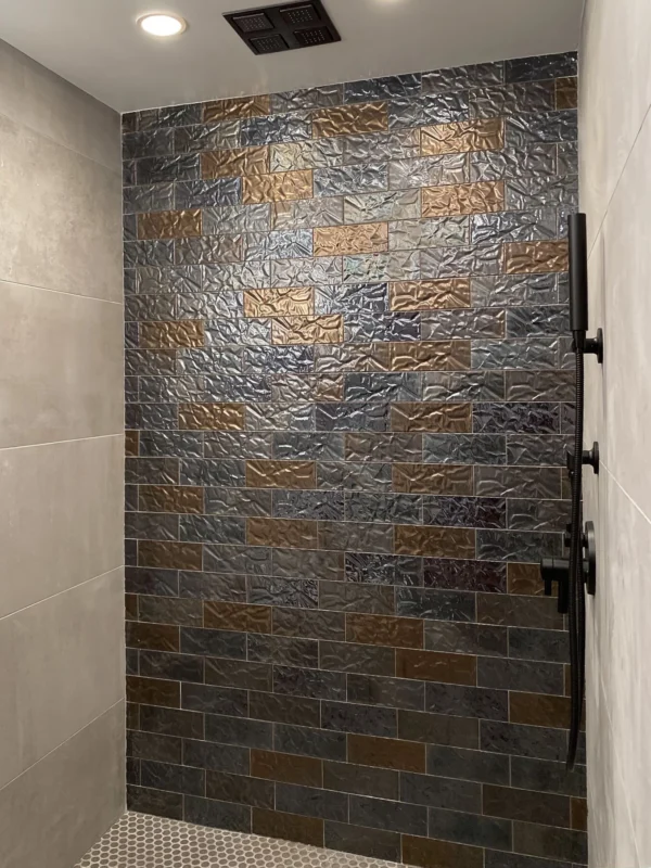 Sleek modern shower design featuring textured tiles, matte fixtures, and elegant hexagonal flooring.