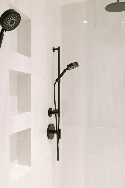 Sleek modern shower design with matte black fixtures and glossy white tile for a minimalist aesthetic.