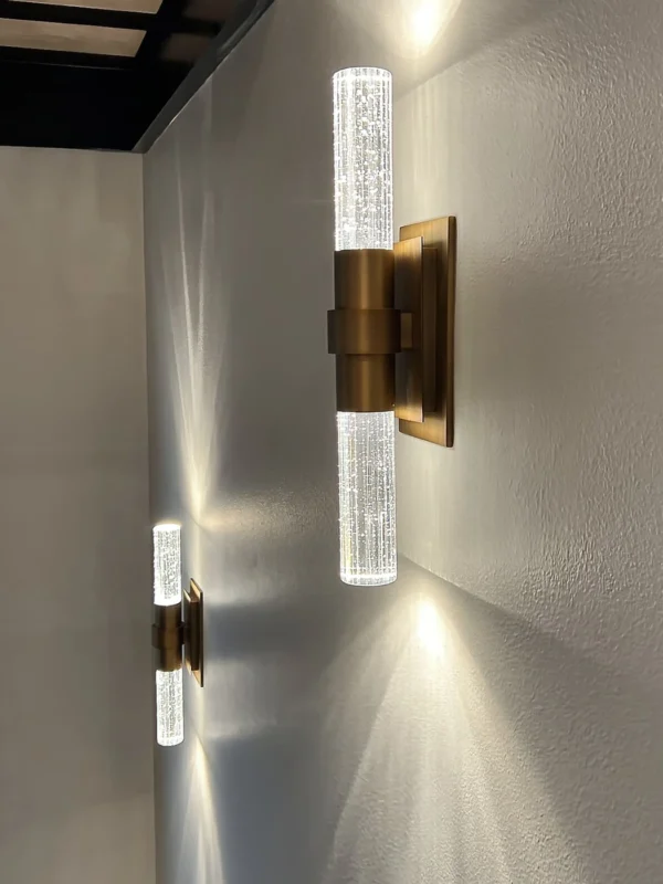 Elegant modern wall sconces in brushed brass with textured glass, providing warm ambient lighting.