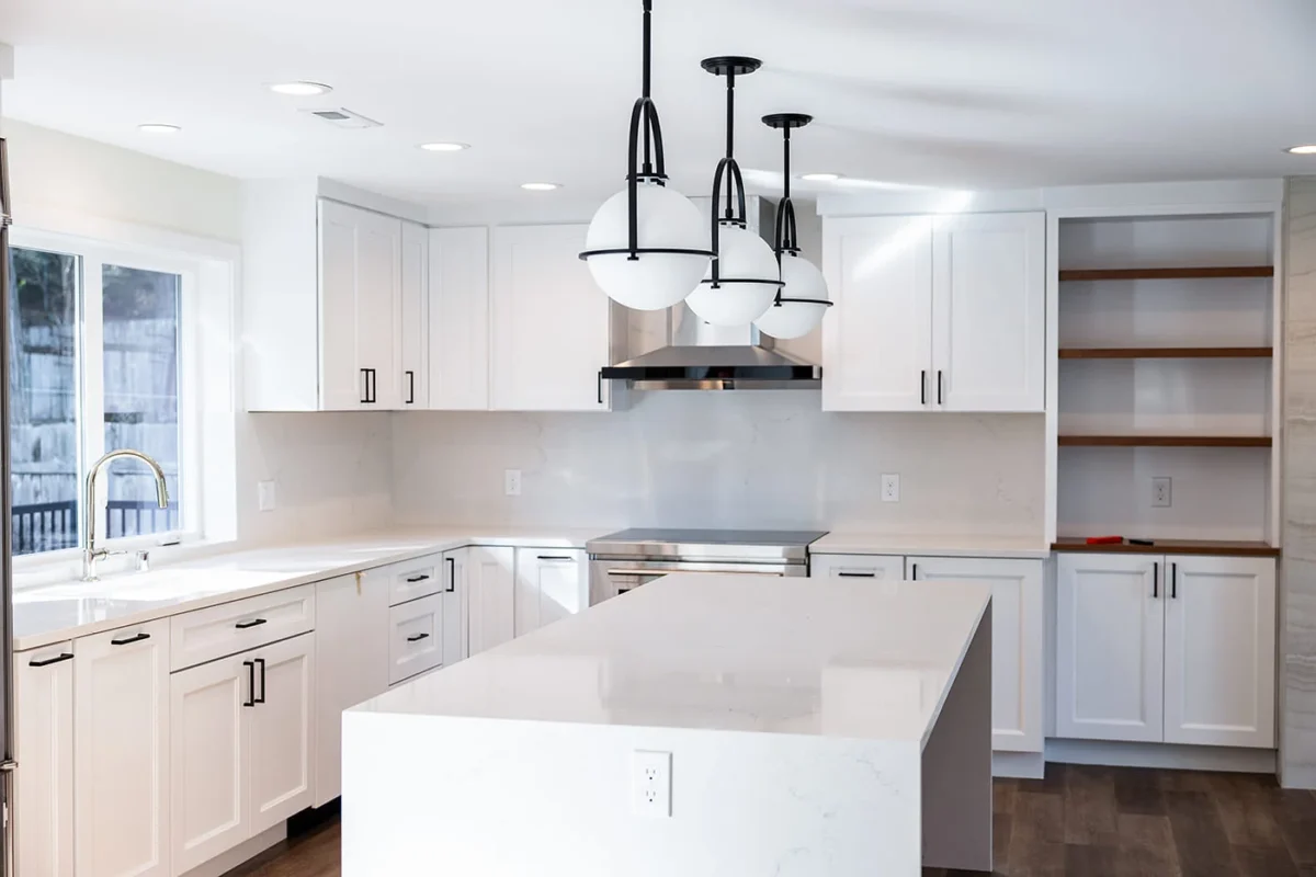 Modern white kitchen design featuring sleek cabinetry, stainless steel appliances, and elegant pendant lighting.