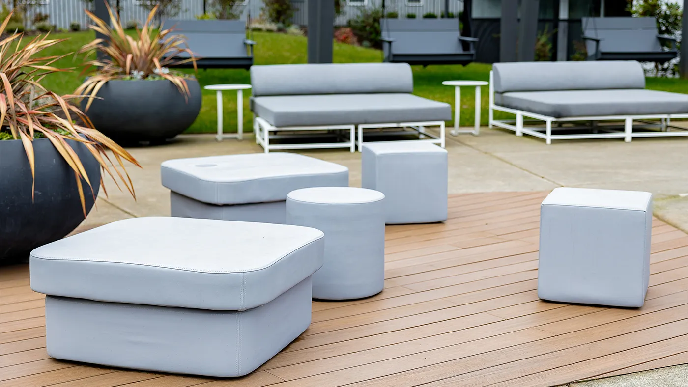 Modern outdoor lounge area with stylish gray seating surrounded by lush greenery.