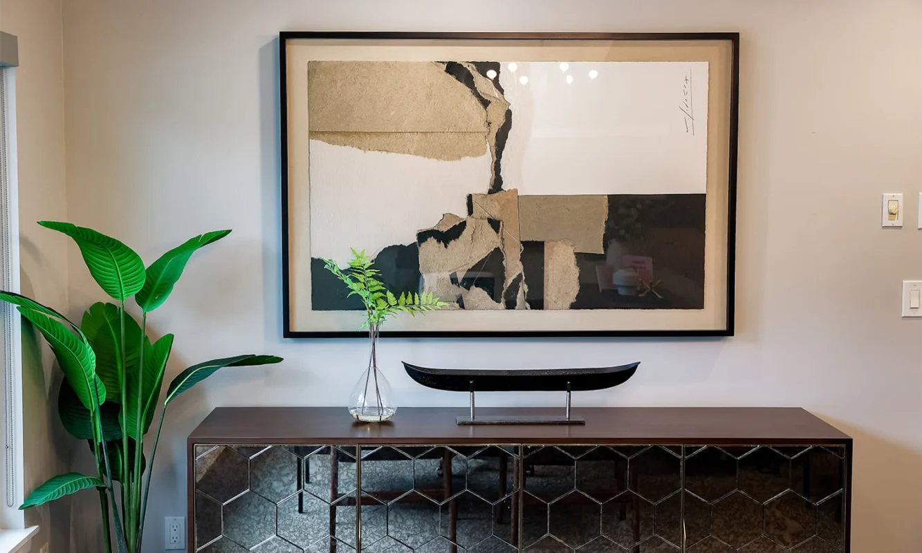 Modern stylish interior with a wooden console table, abstract art, and vibrant greenery.