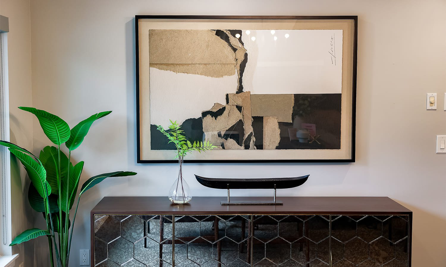 Modern stylish interior with a wooden console table, abstract art, and vibrant greenery.