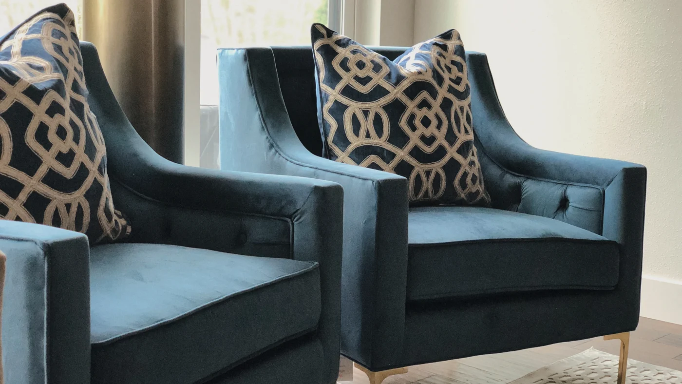 Elegant blue armchairs with gold pillows in a bright, inviting living room setting.