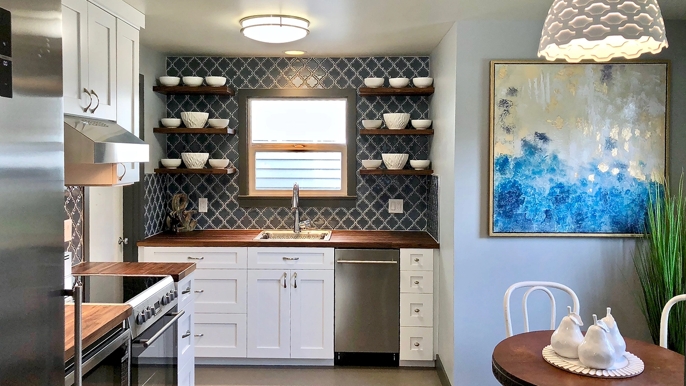 Modern kitchen design featuring white cabinetry, wooden countertops, blue patterned tiles, and stylish decor.