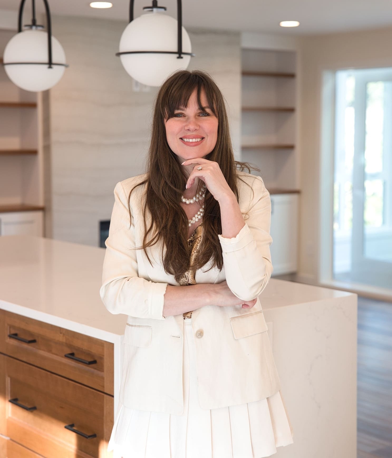 Confident woman in a modern kitchen, showcasing elegance with a stylish outfit and bright decor.