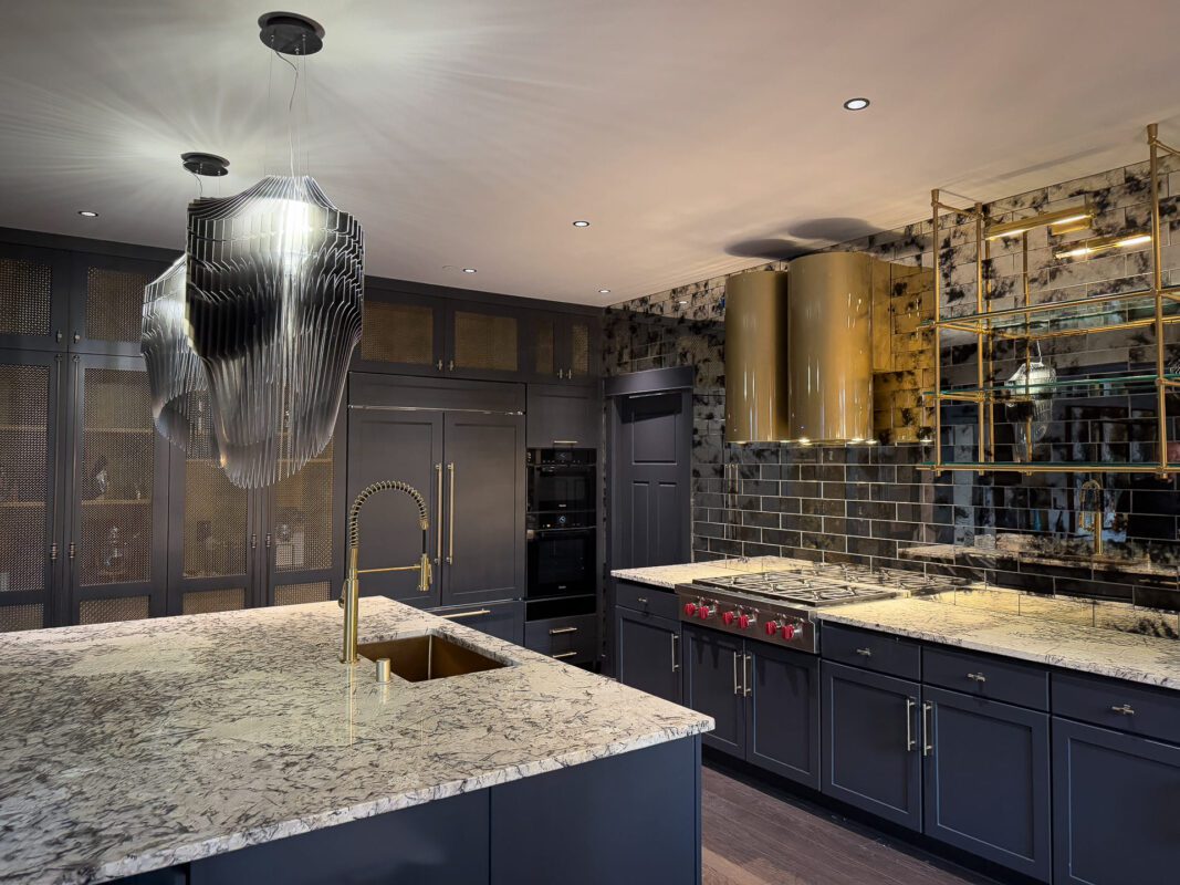 Elegant modern kitchen with dark cabinetry, marble island, gold accents, and state-of-the-art appliances.