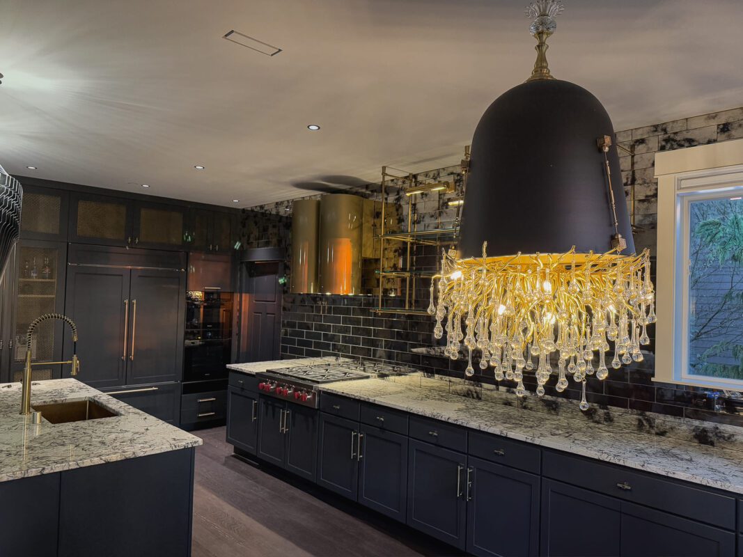 Sleek modern kitchen featuring dark cabinetry, elegant chandelier, and speckled granite countertops.