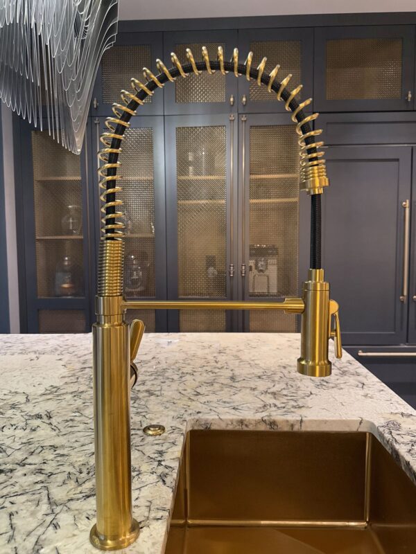 Stylish gold kitchen faucet with coiled design paired with elegant marble countertop.