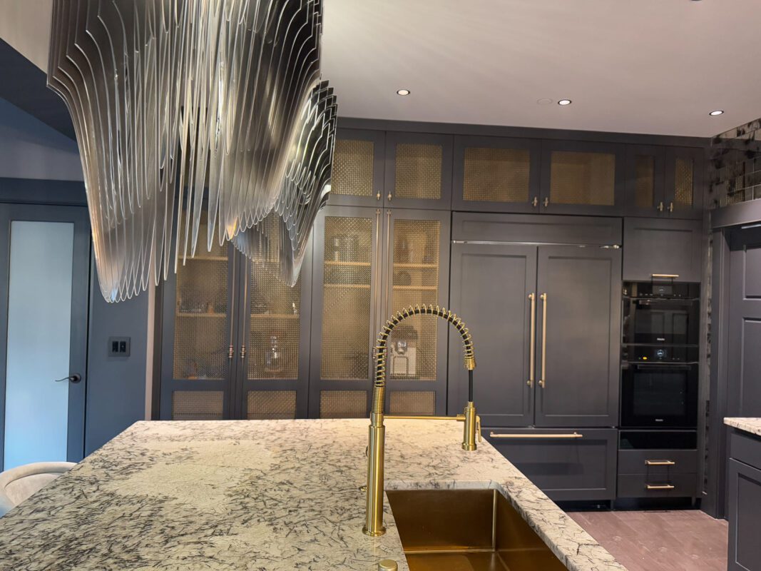 Elegant modern kitchen with navy cabinetry, gold accents, and a stunning stone countertop.