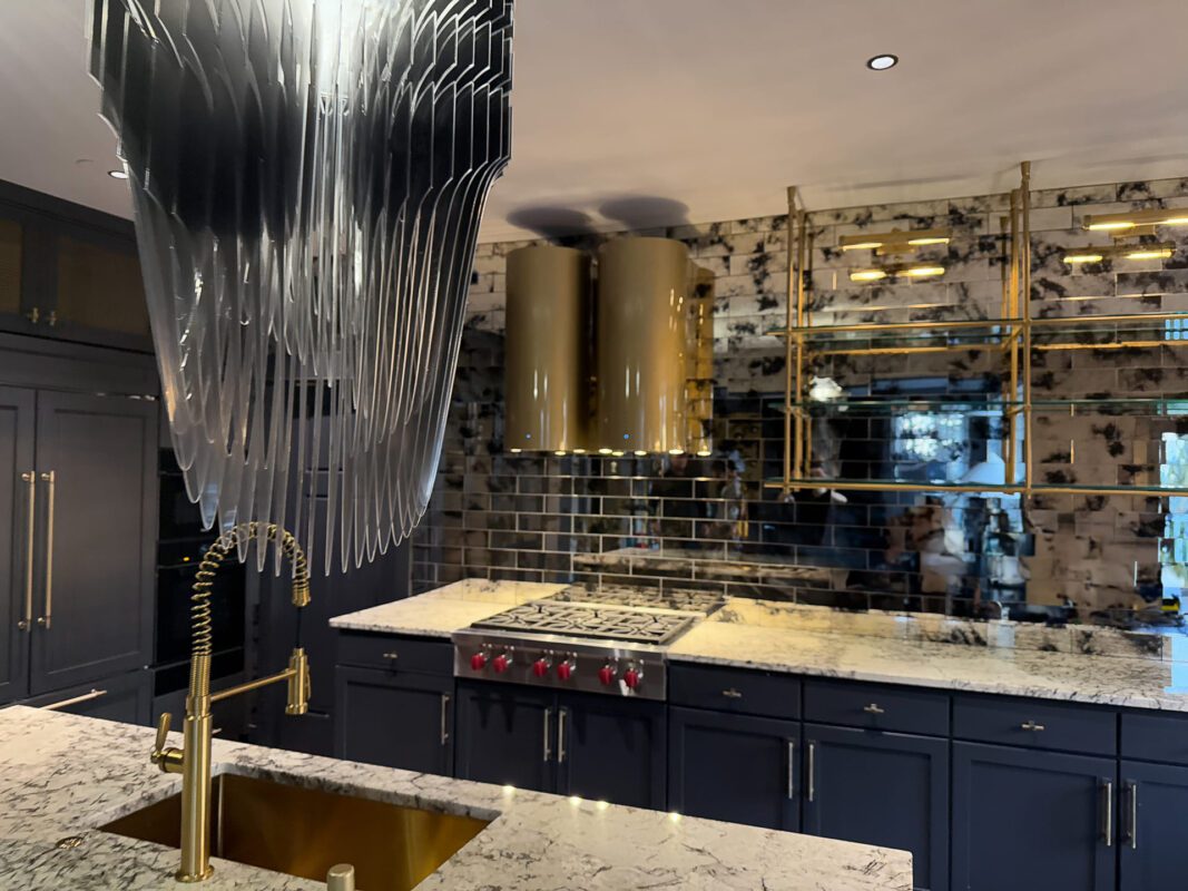 Modern kitchen design featuring navy cabinetry, marble countertops, and unique artistic lighting.