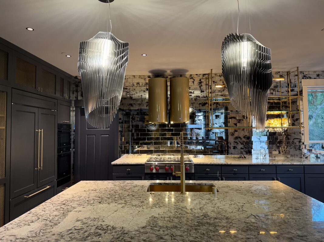 Luxurious modern kitchen with marble island, black cabinetry, and striking pendant lights.