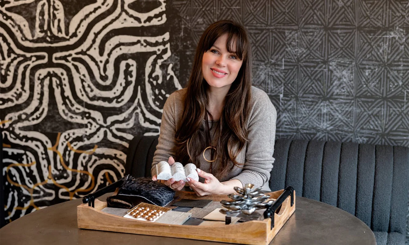 Woman designer showcasing colorful fabric swatches at a creatively designed studio table.