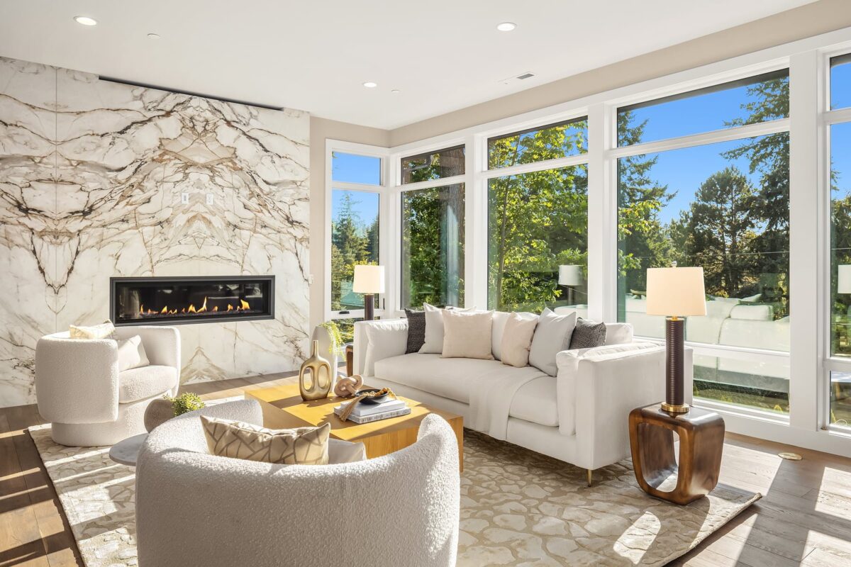 Sophisticated modern living room with marble fireplace, plush seating, and abundant natural light.