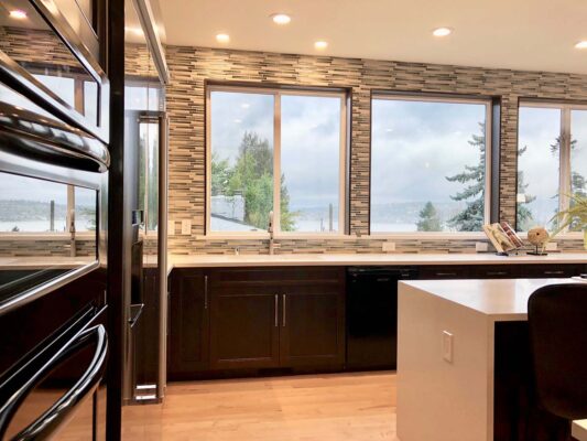 Elegant dining area with curated accessories, warm lighting fixtures, and a view of the Pacific Northwest outdoors, reflecting sophisticated interior styling.