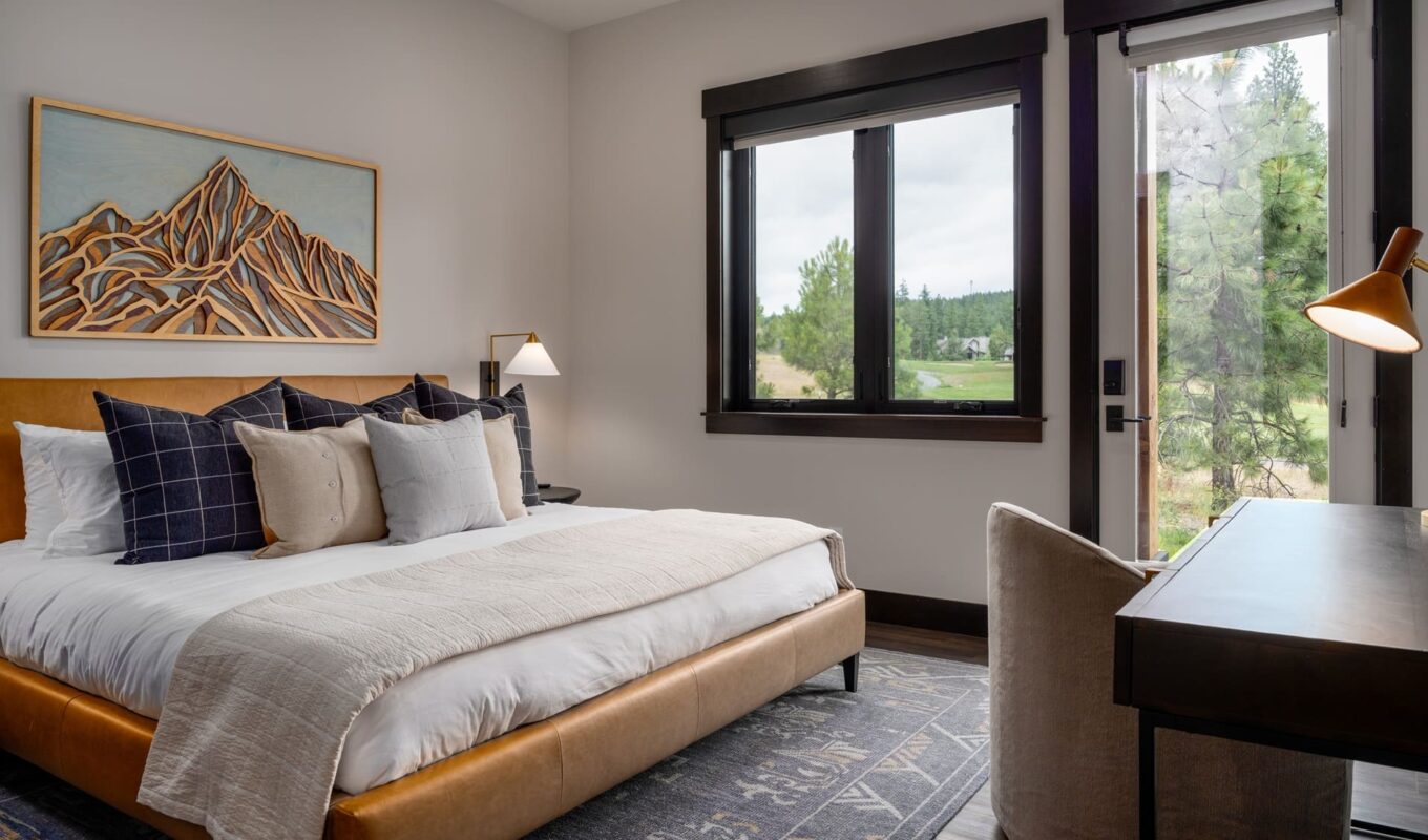 Stylish modern bedroom with plush bed, cozy decor, and natural light from large windows.