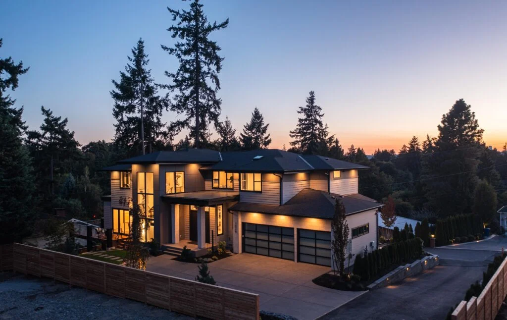 Modern architectural home surrounded by nature, showcasing elegant design and inviting evening ambiance.