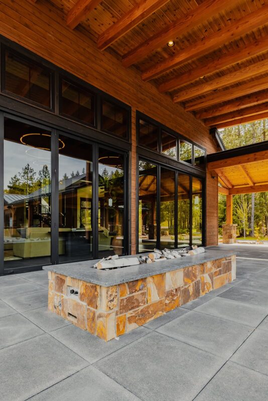 Elegant outdoor living space with modern fire pit, lush garden, and seamless indoor-outdoor flow.