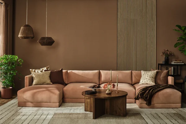 Cozy modern living room featuring a blush pink sectional, dark wood coffee table, and greenery.