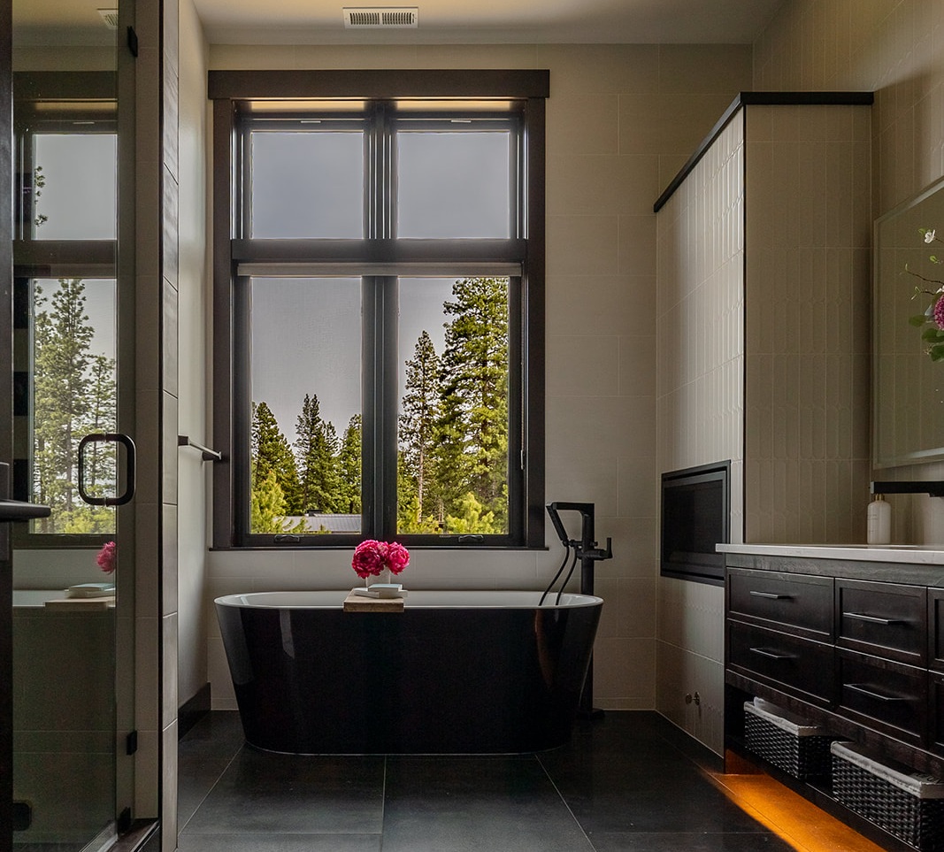 Modern walk-in shower featuring black fixtures, light gray wall tiles, and a built-in bench illuminated by soft LED accent lighting.