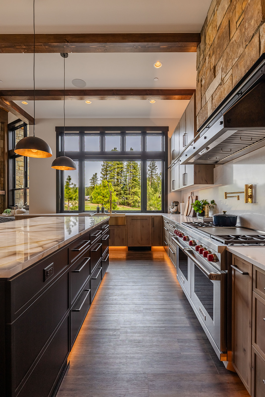 Custom kitchen design in Suncadia showcasing natural wood cabinets, black island base, and integrated LED under-cabinet lighting.