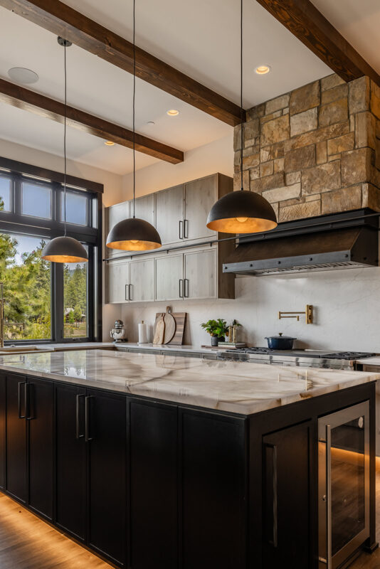 Luxury Suncadia kitchen with quartzite countertops, exposed wood beams, and large windows overlooking forest views.