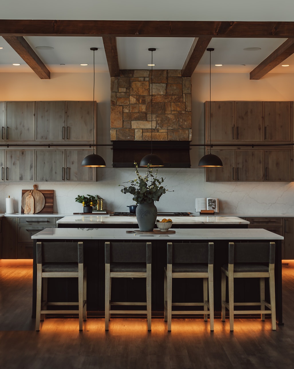 Luxury Suncadia kitchen with quartzite countertops, exposed wood beams, and large windows overlooking forest views.