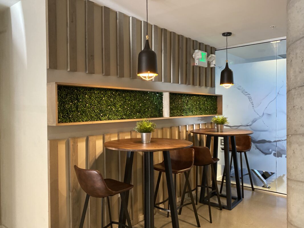 Lounge area showing white entry door, high-top tables, leather stools and green inset wall feature.