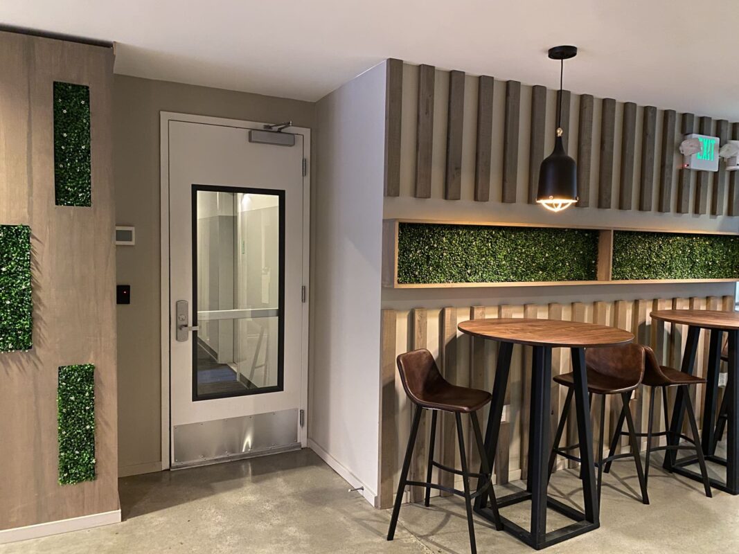 Wider view of apartment lounge with mixed seating, gold tables and vertical wood partitions.