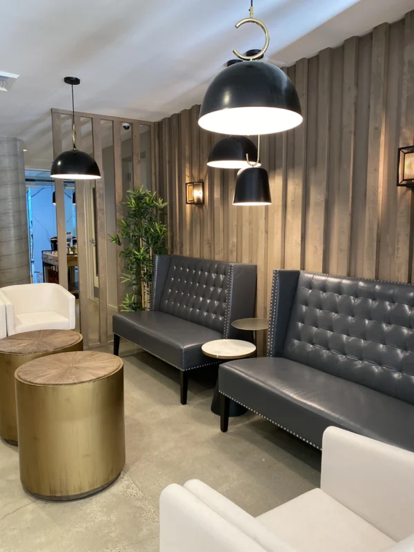 Close view of charcoal tufted high‑back lounge sofas with studded trim and nesting side tables.