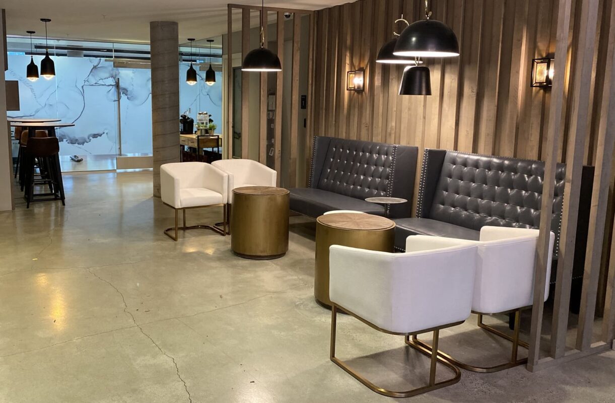 Lobby entrance featuring large Beryl stamped art wall, faux green inserts and white lounge chair.