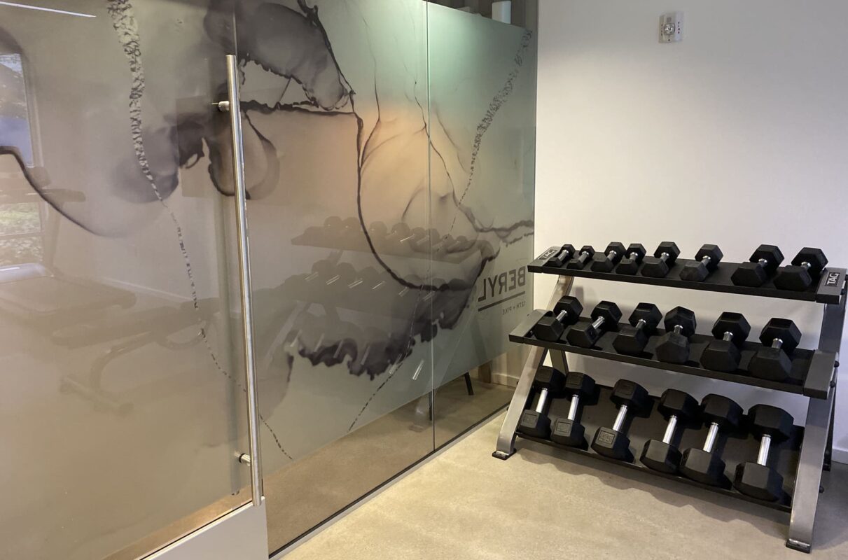 Compact apartment gym with dumbbell rack, bench, treadmill and wall-mounted TV.