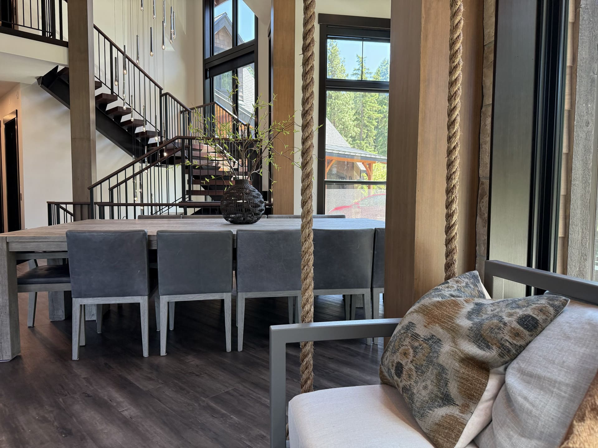 Suncadia dining room with gray leather chairs and rope wrapped wood column, looking past toward the floating staircase and pendant cascade beyond.