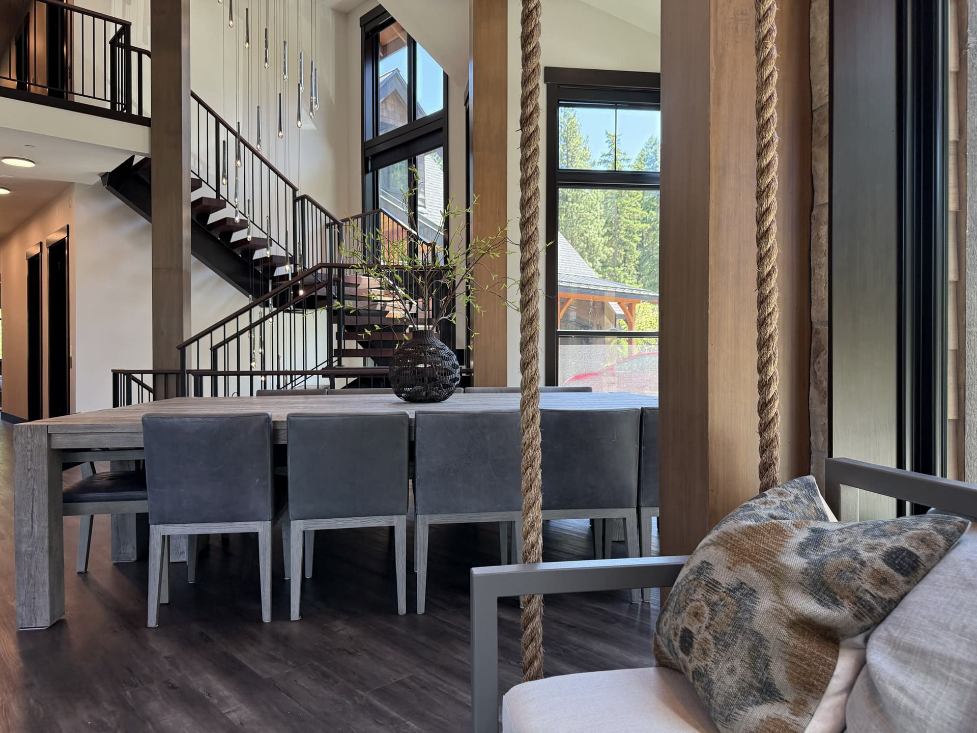Dining area in the Suncadia home with leather chairs and wood column in the foreground and the floating staircase with pendant cascade behind.